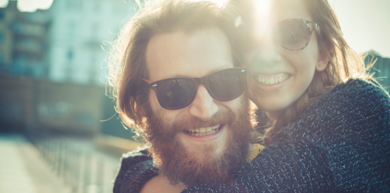 Ein lachendes Paar mit Sonnenbrillen im Sonnenschein