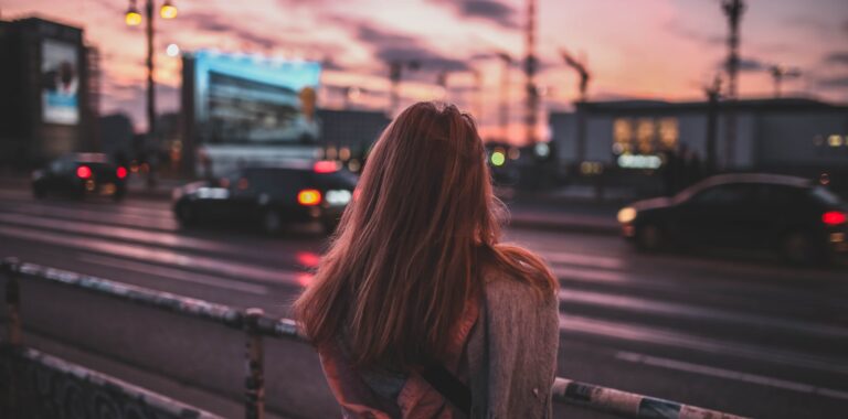 woman from the back in front of a street during sunset