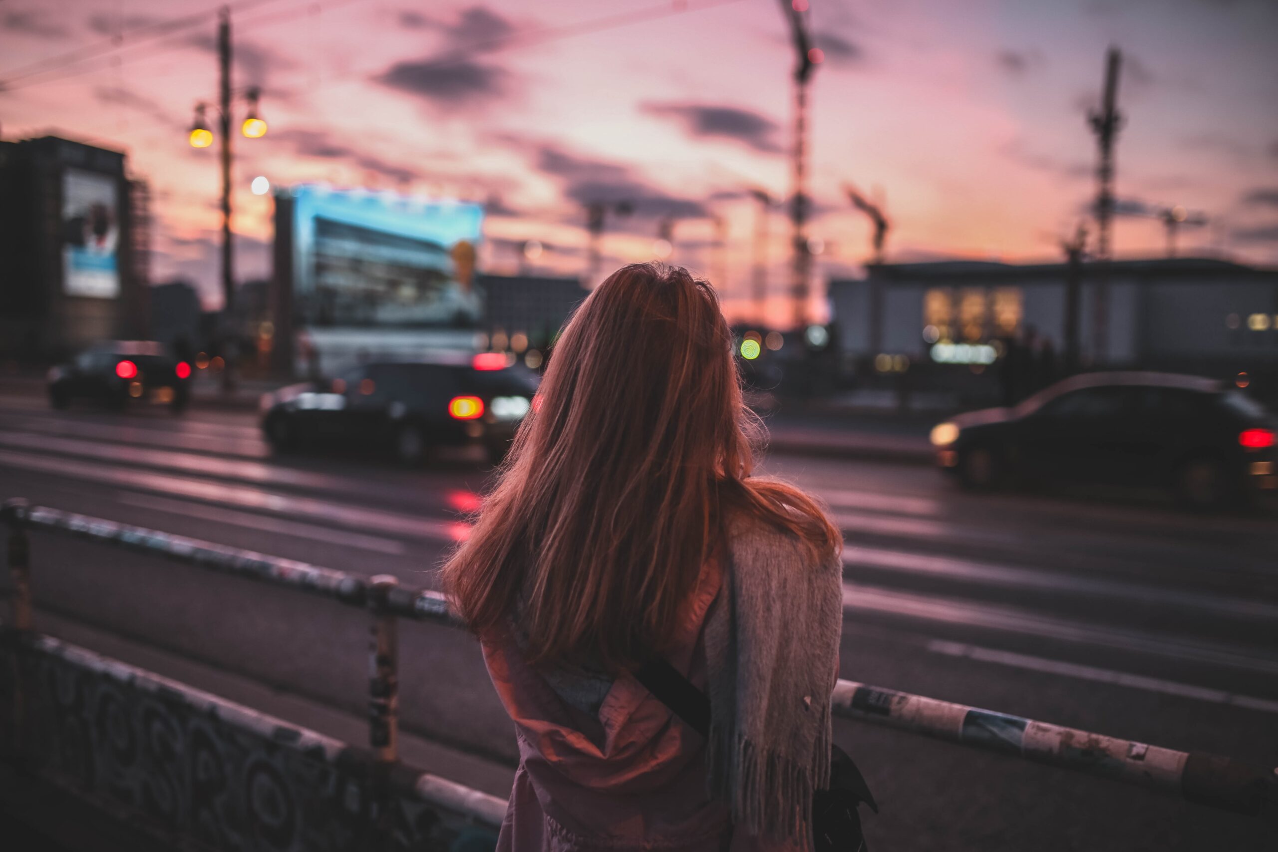 woman from the back in front of a street during sunset