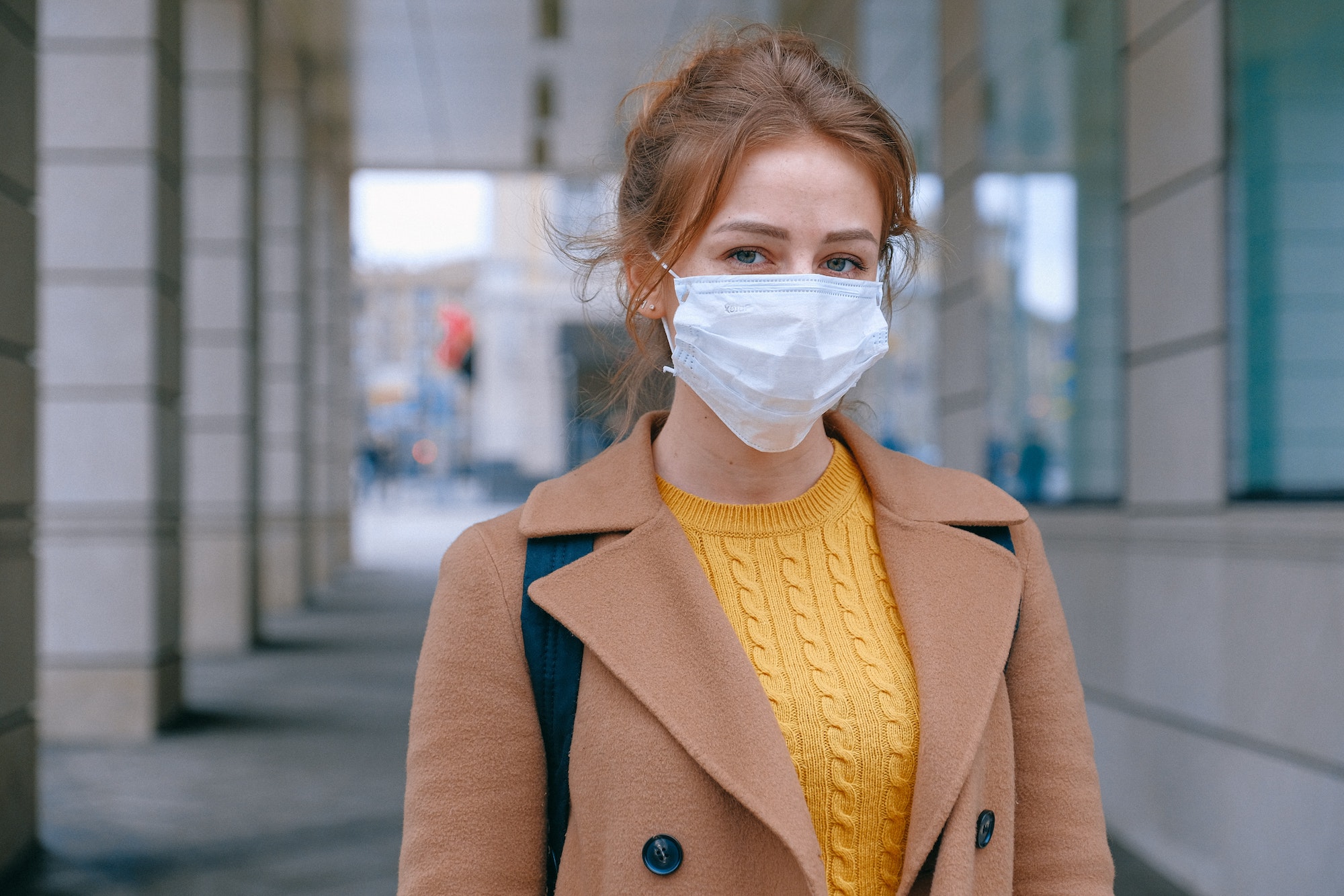 Junge Frau vor Gebäude mit Maske