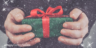 Hände halten ein Geschenk | Untertitel: Happy Giving Season