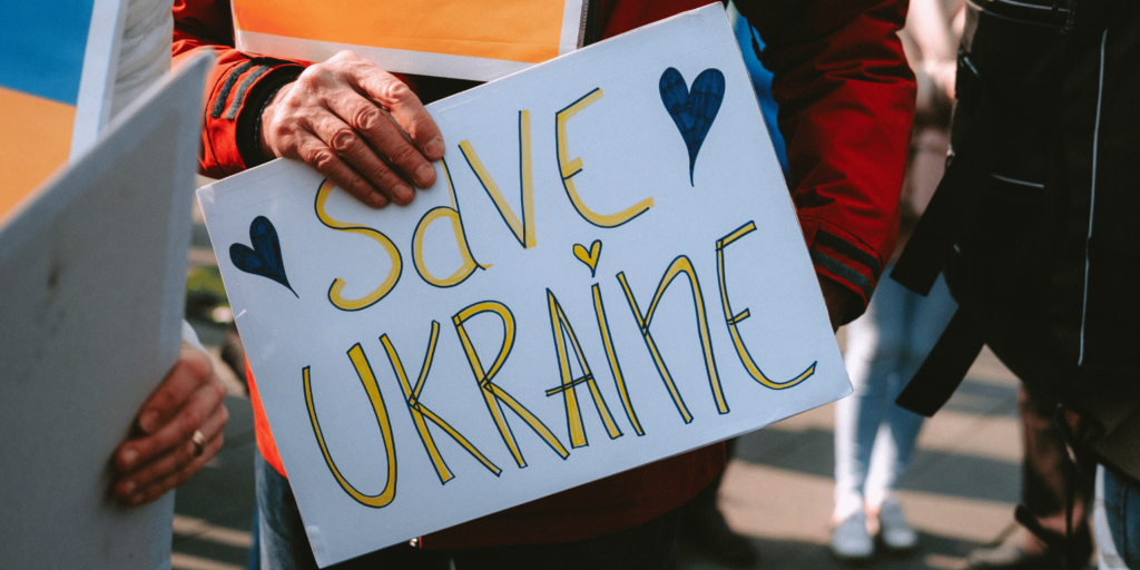 Person hält Plakat mit der Aufschrift "Save Ukraine"