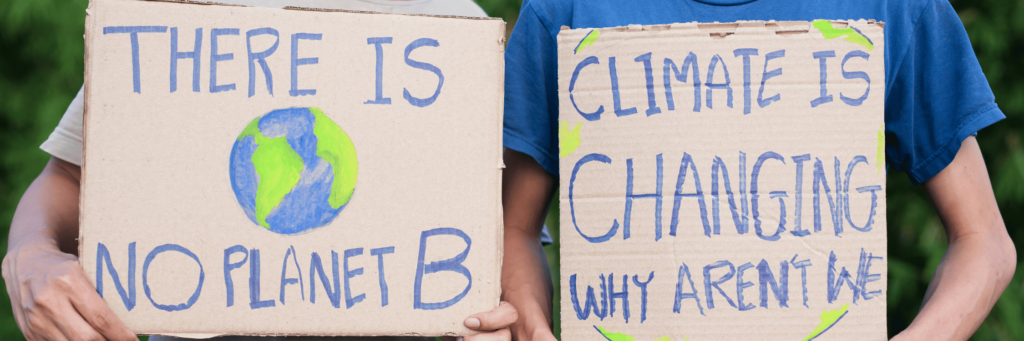 Zwei Personen halten Schilder hoch mit der Aufschrift: "There is no Planet B" und "Climate is Changing, why aren't we?"