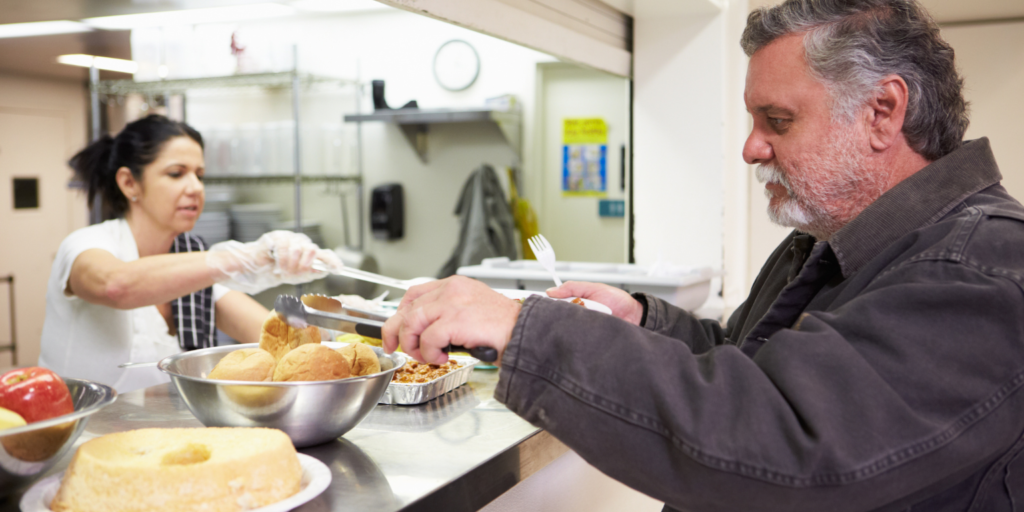 Mann bekommt Essen in der Obdachlosenhilfe ausgegeben