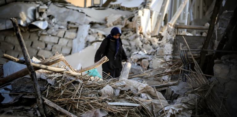 Frau steigt über die Trümmer eines zerstörten Hauses