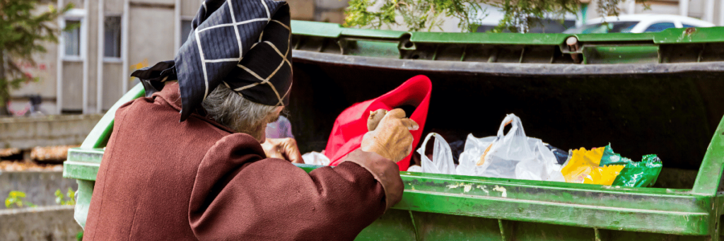 An elderly woman searches a garbage can