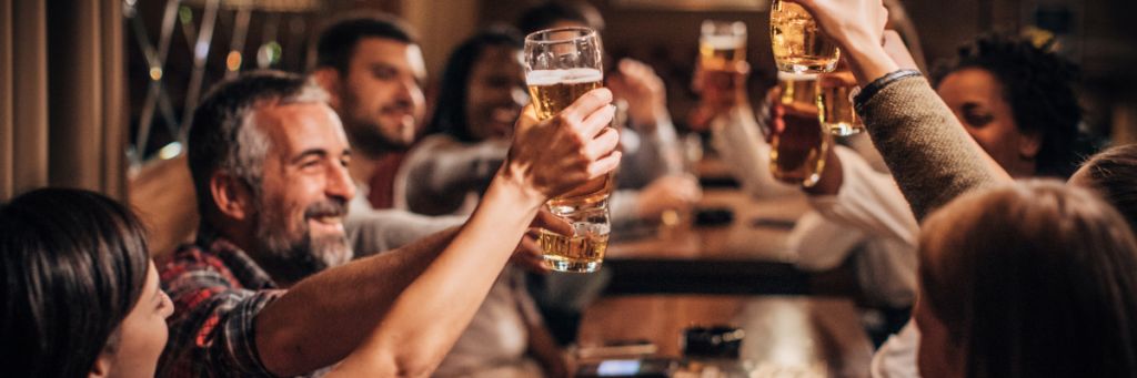 A few people clink glasses of beer together.