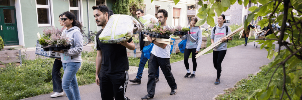 Ehrenamtliche tragen Material für den Bau eines Hochbeets