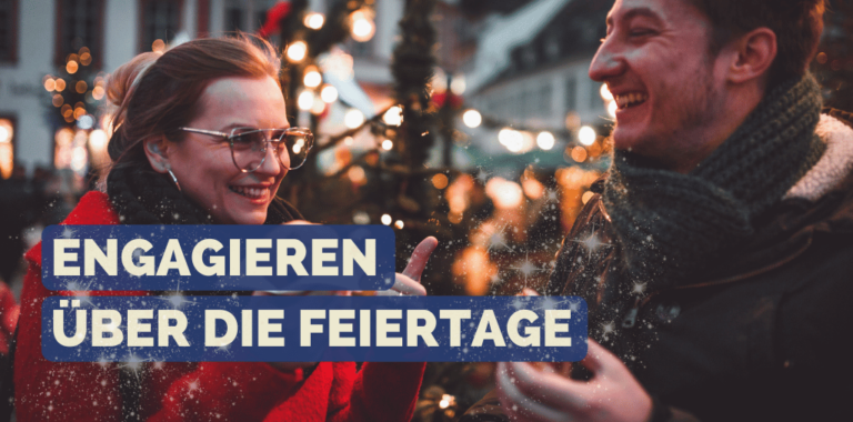 Mann und Frau lächeln sich an während sie auf dem Weihnachtsmarkt stehen