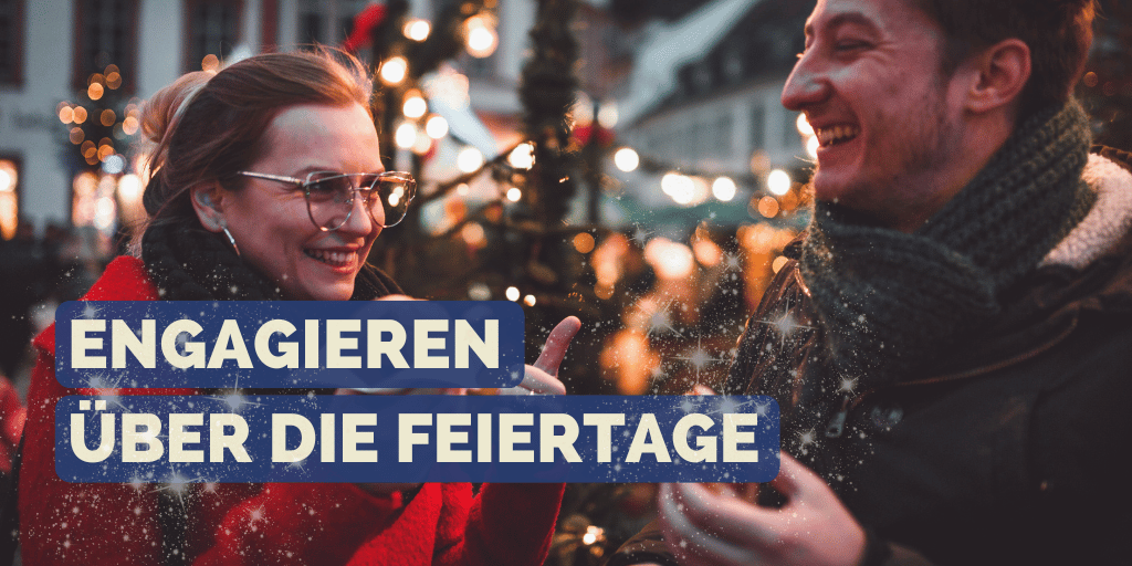 Mann und Frau lächeln sich an während sie auf dem Weihnachtsmarkt stehen