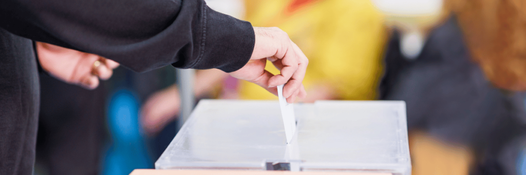 Mann steckt Stimmzettel eine Wahlurne