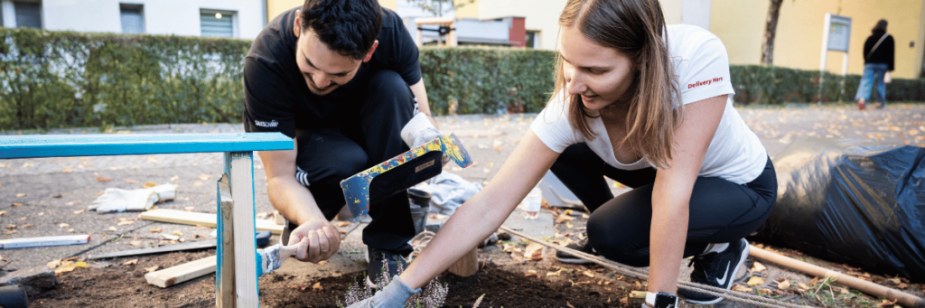 Two people paint a homemade wooden bench with blue paint.  