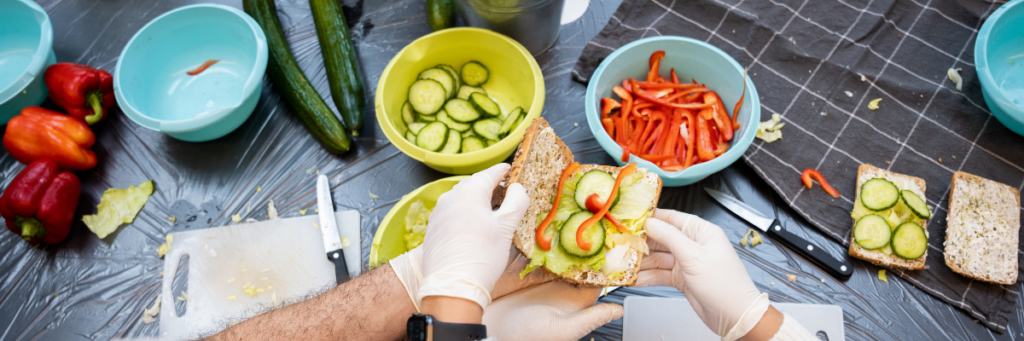 Ein Sandwich wird gemeinsam belegt, mit viel frischem Gemüse.