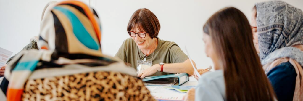 Intermediate picture: Volunteering for democracy and human rights - women in a working group, getting something explained.